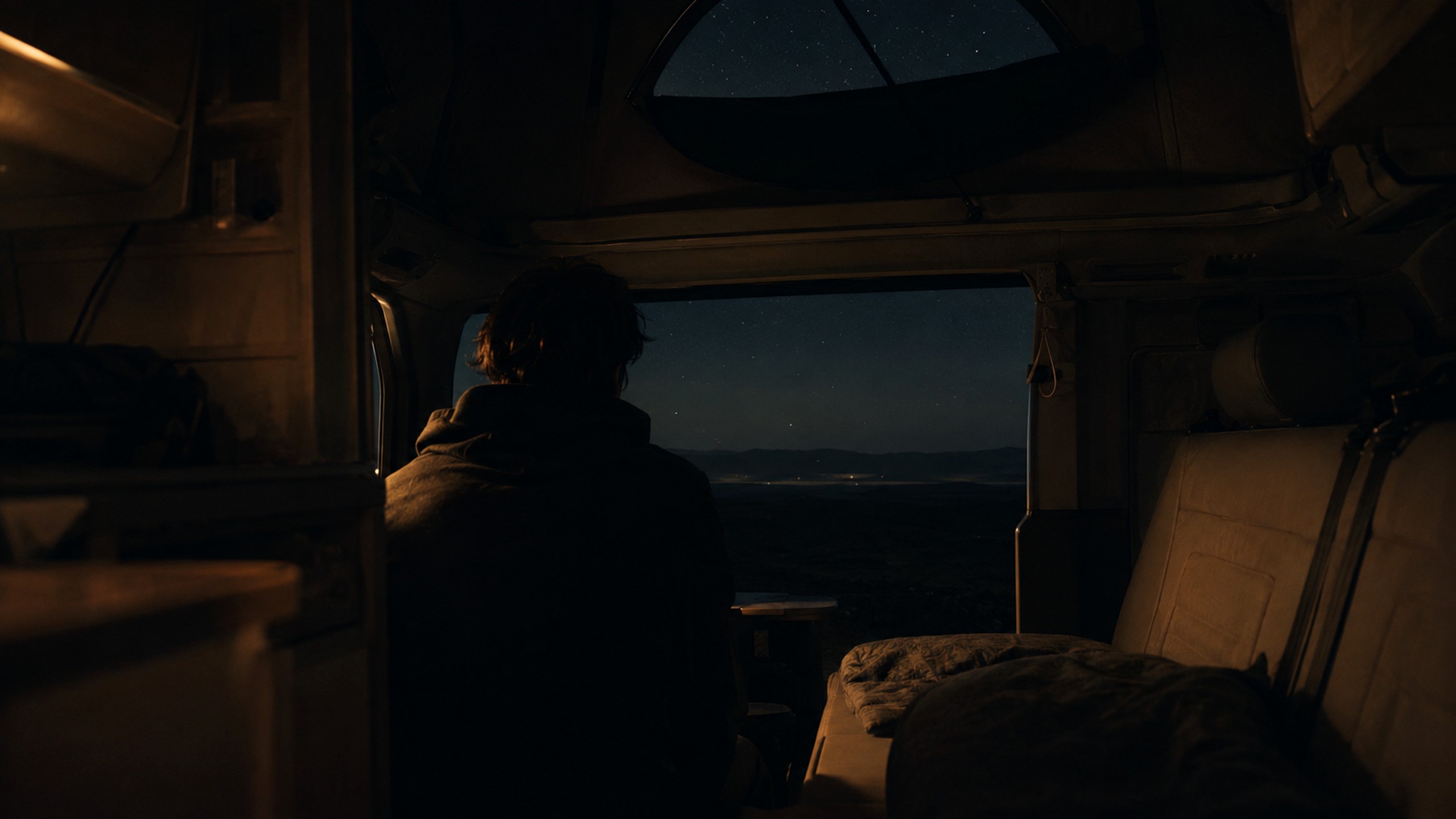 Anonyme Silhouette sitzt nachts still im dunklen Campingbus und blickt hinaus