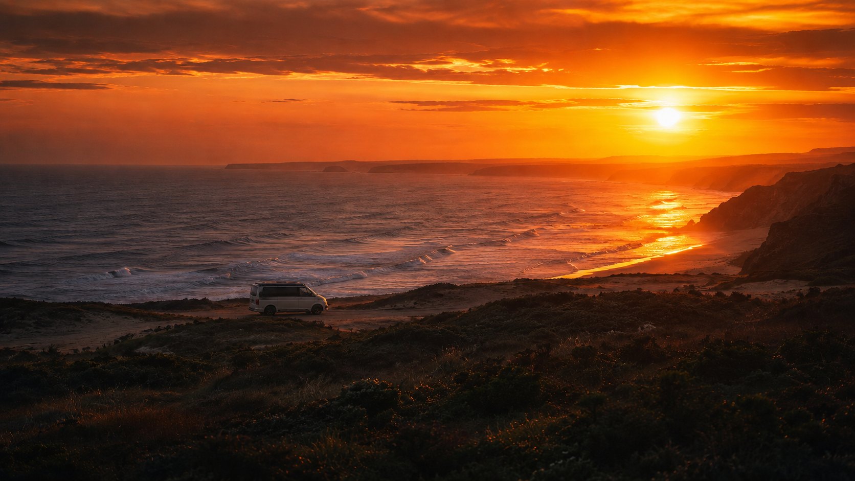 Sonnenuntergang über dem Atlantik mit Campervan zwischen den Dünen