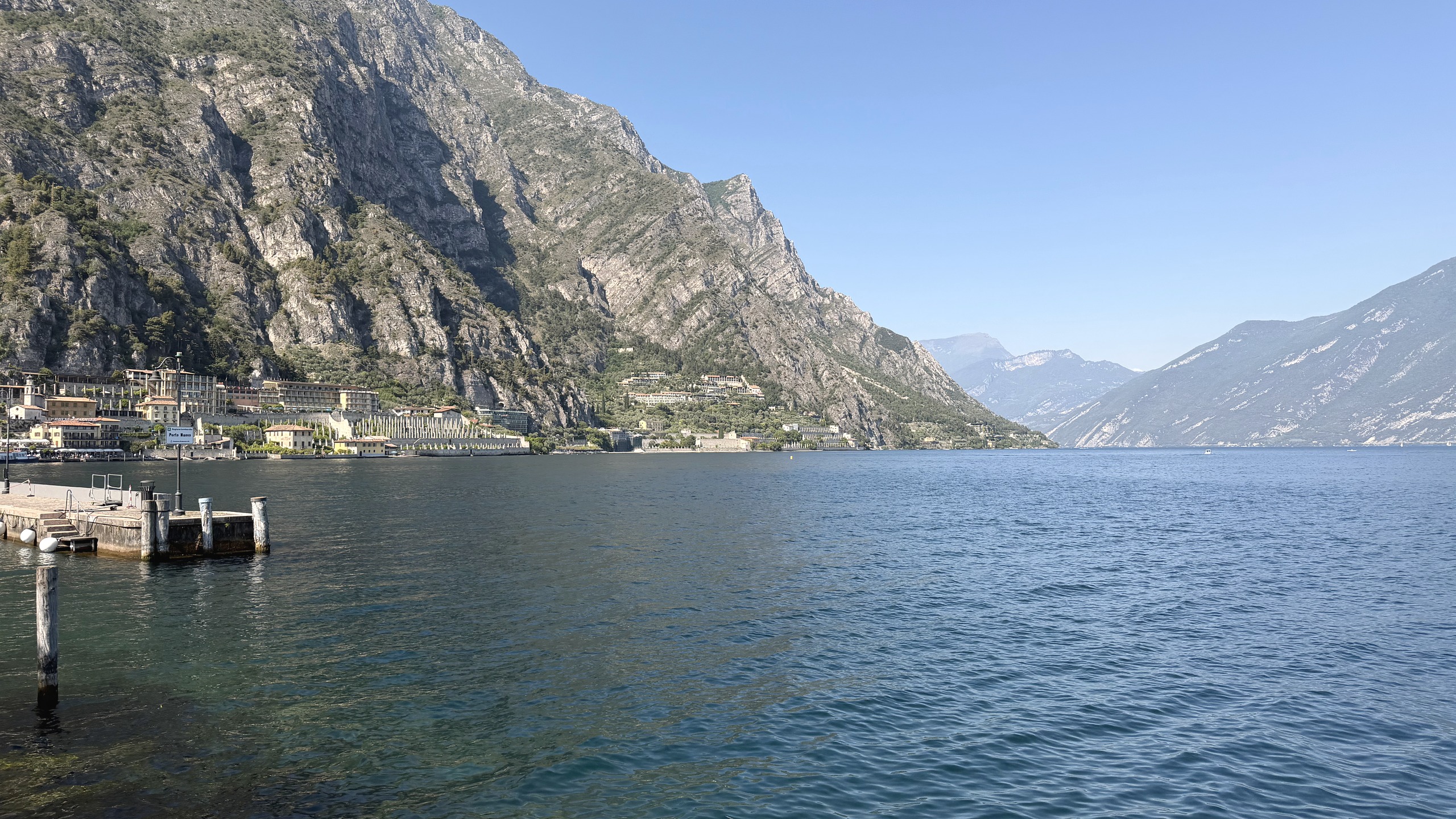 Blick über den Gardasee auf Steilwände und den Uferort Limone im hellen Morgenlicht